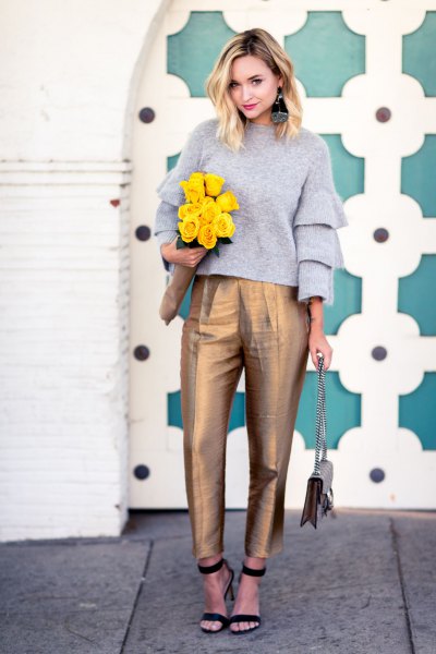 Gray crew neck sweater with ruffled sleeves and gold high waisted chinos