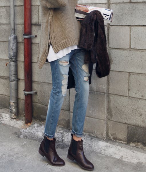 Gray sweater with side slits, ripped jeans and black zipped leather boots