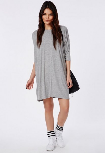 gray t-shirt dress with black leather shoulder bag and white running shoes