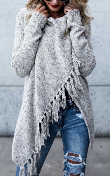 Gray tunic wrap sweater with fringes and blue destroyed jeans