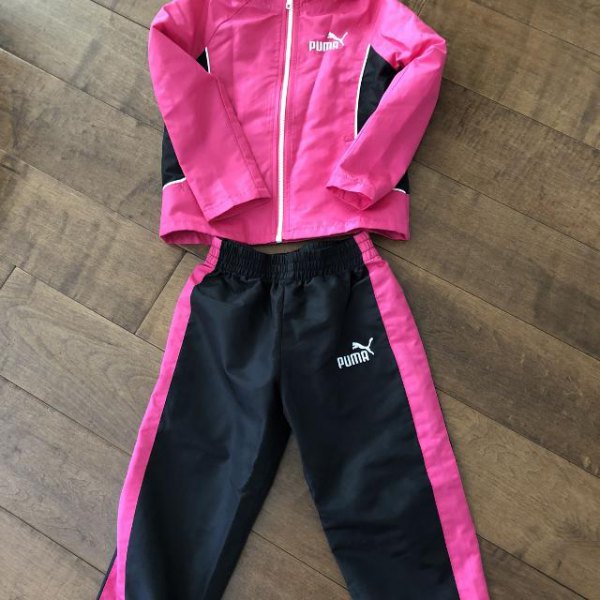 a pink windbreaker with black running pants