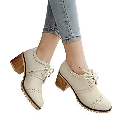 Ivory wingtip shoes with light blue skinny jeans