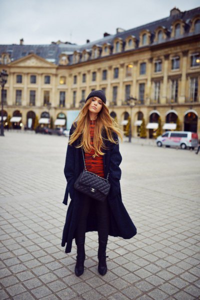 long black coat with orange sweater and knitted hat
