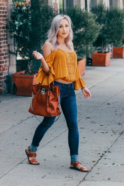 Wear a mustard off shoulder crop top with ruffle sleeves and blue skinny jeans