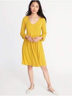 Mustard yellow, knee-length, flared dress with a V-neckline and white ballet flats