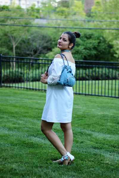 Off-the-shoulder white mini blouse dress with a light blue jeans
backpack