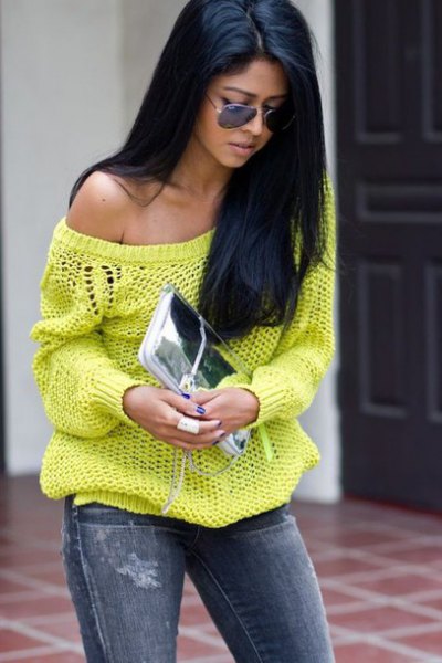 One shoulder yellow sweater with jeans and silver clutch bag