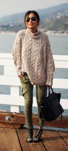 Light pink oversized cable knit sweater and green skinny cargo jeans