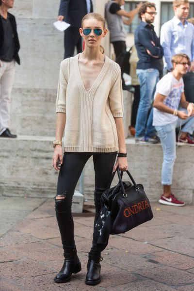 Light pink sweater with a deep V-neck, black ripped jeans and short boots