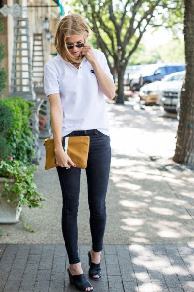 Polo shirt with dark blue skinny jeans and a brown leather clutch