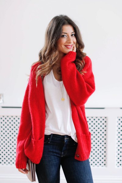 Red chunky cardigan sweater with white scoop neck t-shirt and dark blue skinny jeans