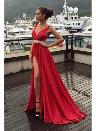 Red, floor-length dress with a high slit, a belt and black heels