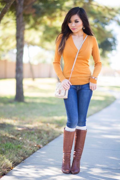 Mustard V-neck bodycon sweater, blue jeans and gray knee high boots