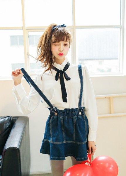 White button down shirt, black bow tie and navy blue pleated suspender skirt