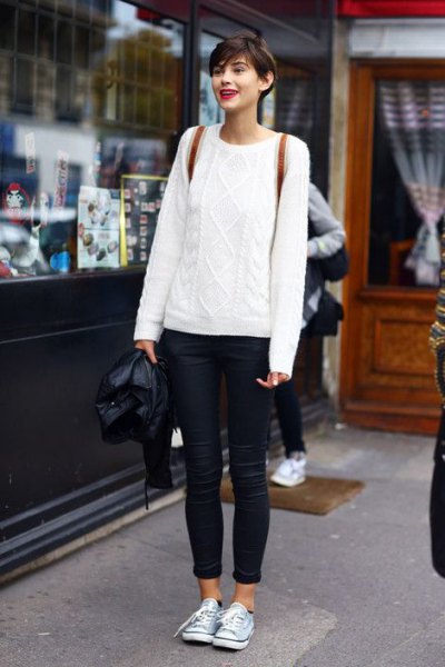White large cable knit sweater and blue cuffed skinny jeans