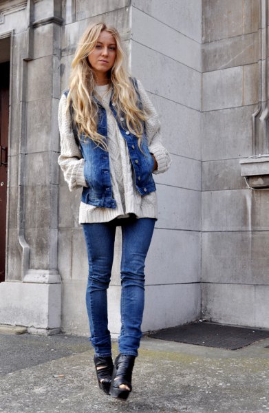 White cable knit sweater with blue denim motorcycle vest and boots