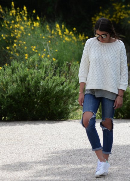 White cable knit sweater with ripped blue cuffed jeans
