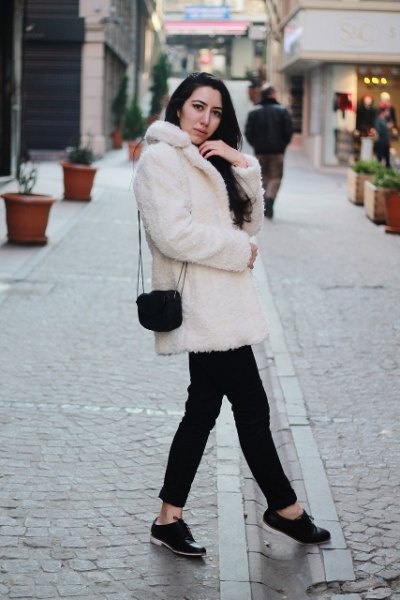 White coat with faux fur collar, black jeans and suede shoes