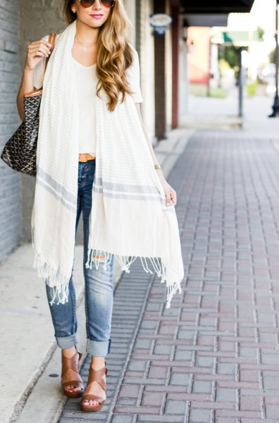 White long fringed scarf worn with white cropped t-shirt and blue cuffed jeans