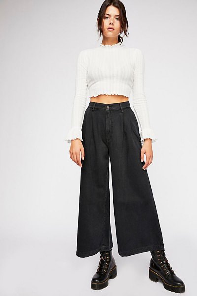 White cropped sweater with a stand-up collar and black pleated jeans