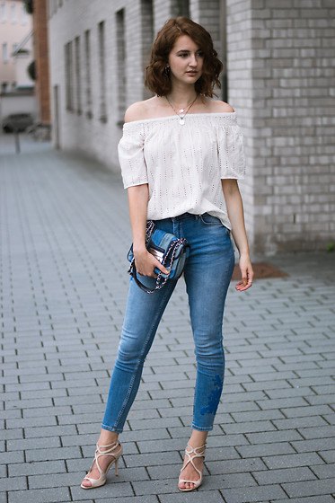 White off-the-shoulder blouse with skinny jeans and a blue jeans
clutch