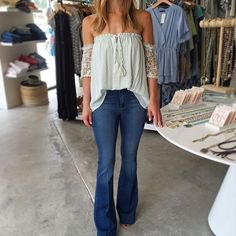 White off the shoulder pleated blouse with flared blue jeans