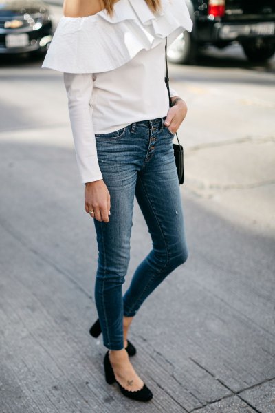 White one-shoulder blouse with ruffles at shoulder and button-down jeans