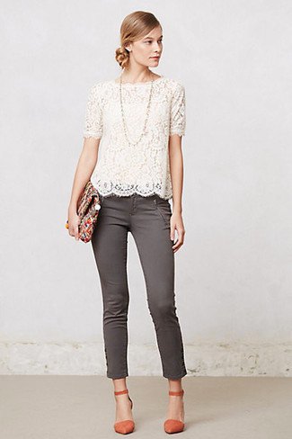 White, short-sleeved, lace blouse with a scalloped hem and grey, ankle-length drainpipe jeans