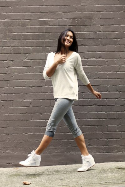 White scoop neck sweater and gray knee length skinny jeans