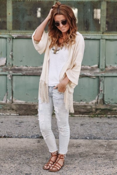 white top with ivory fringed cape with half sleeves and light gray jeans