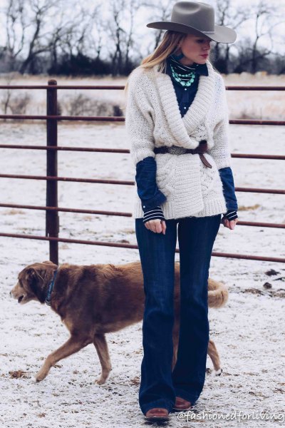 Belted white wrap sweater, blue flared jeans, and black square-toe boots