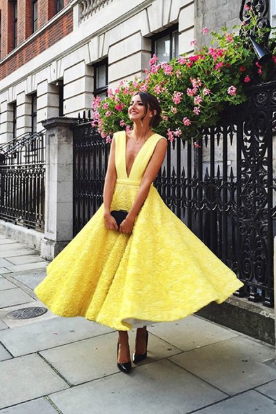 Yellow lace flared midi dress with a deep V-neckline and black
heels